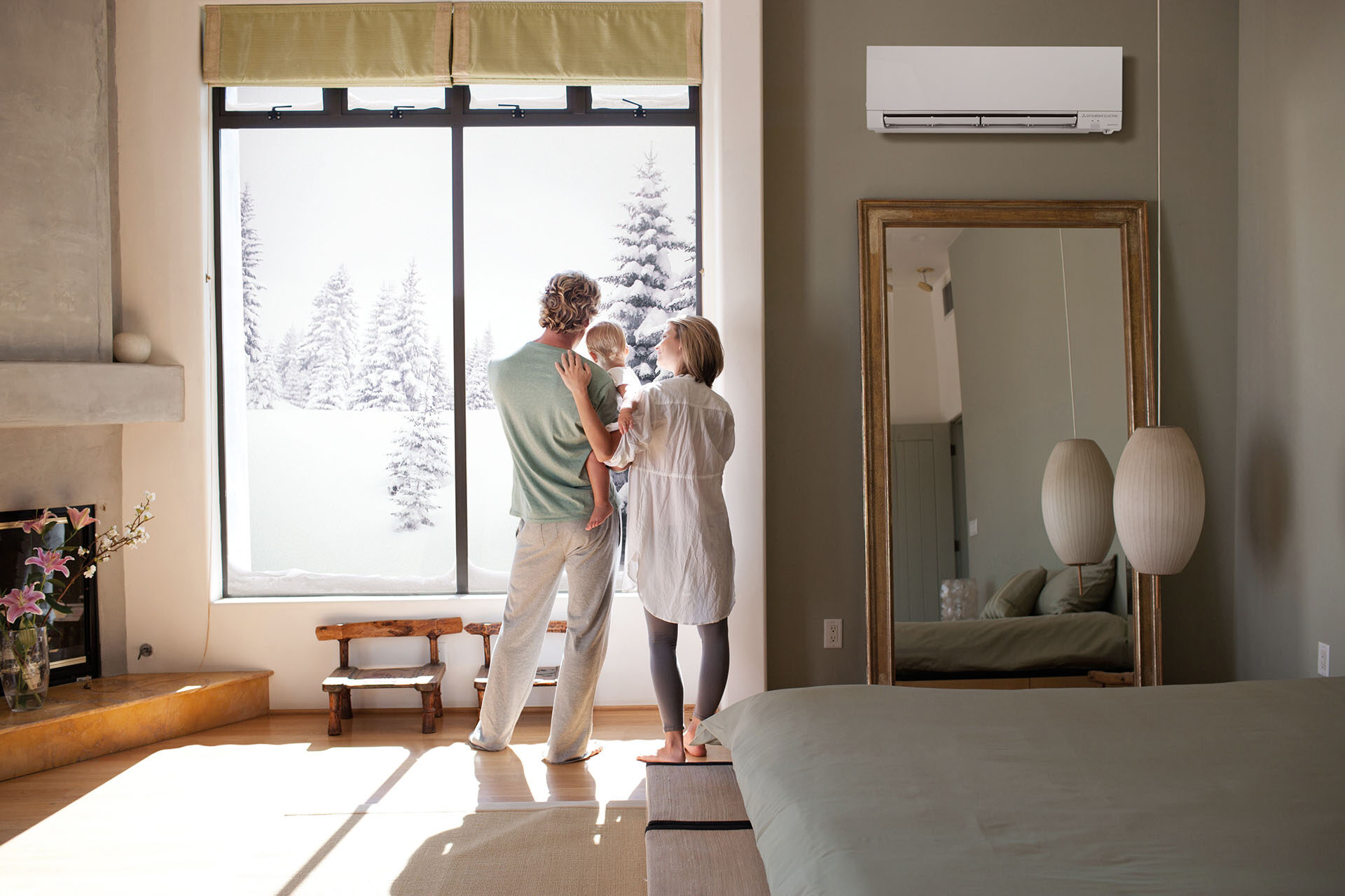 A couple holding their baby in front of a window with a snowy landscape outside