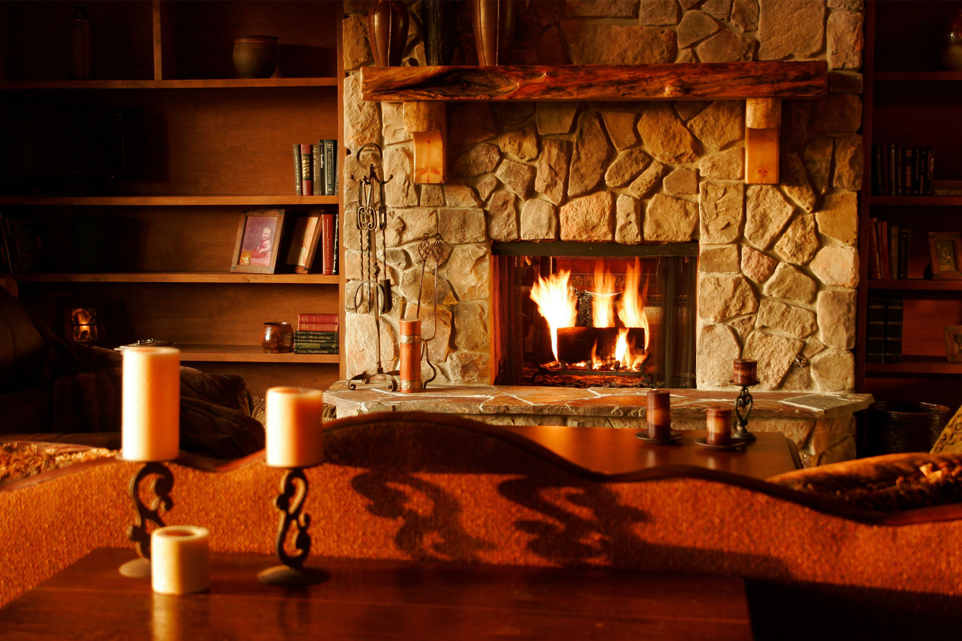 A cozy living room with a fire in a stone fireplace