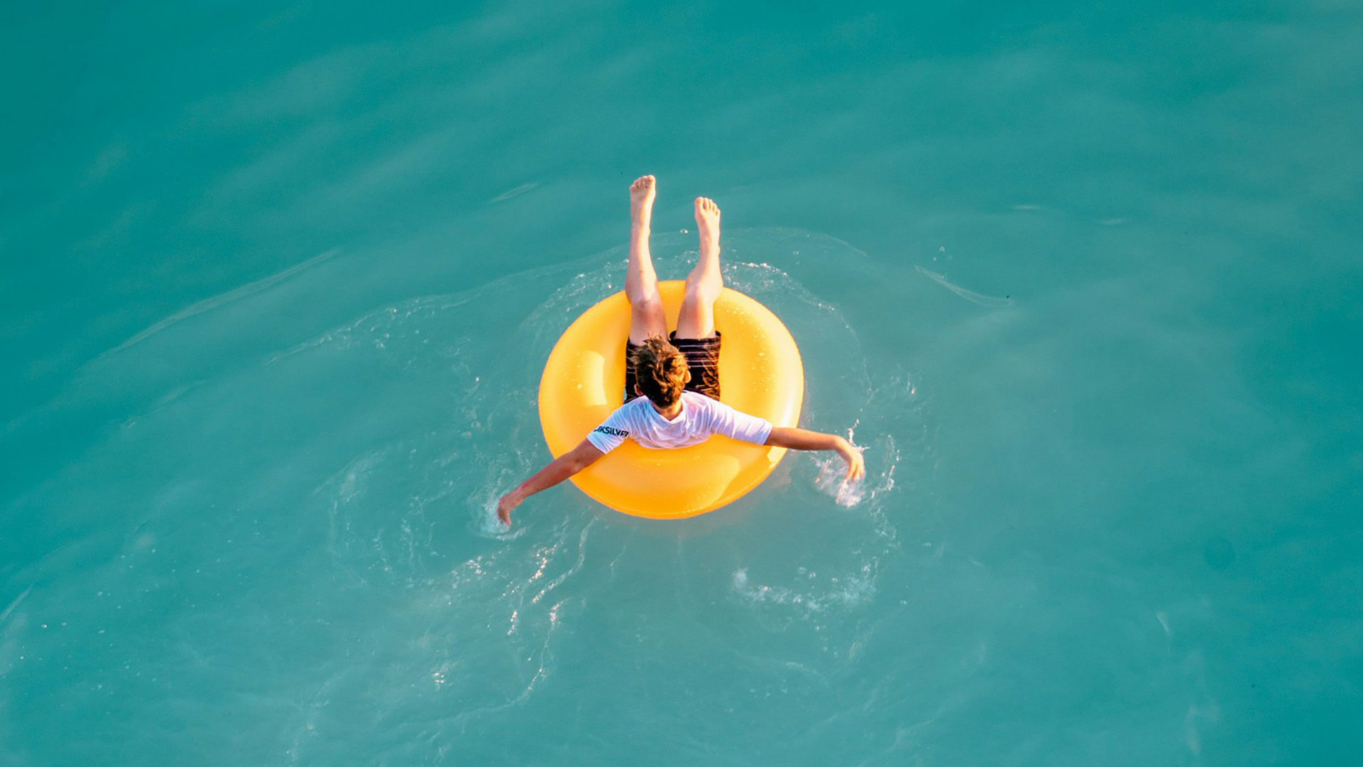 Person floating in a yellow tube in a pool